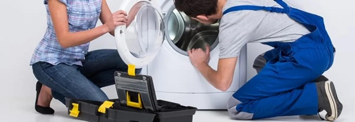 Washer repair technician inspecting a front-load washing machine with tools in Milwaukee, WI