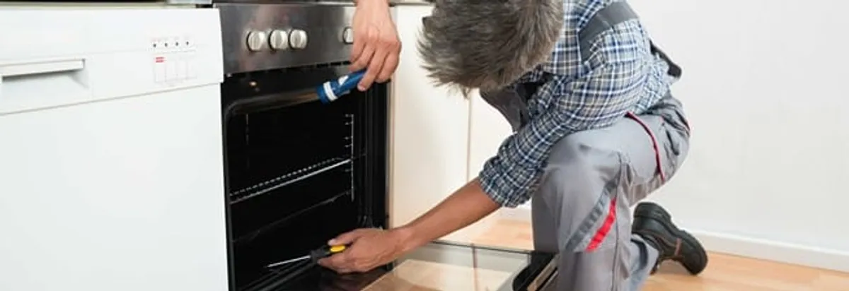 Oven repair technician inspecting and servicing an electric oven in Milwaukee, WI