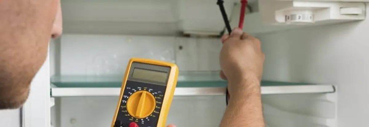 Refrigerator repair technician testing electrical components with a multimeter in Milwaukee, WI