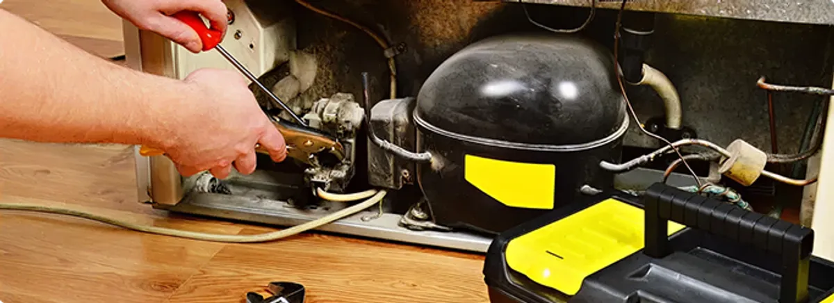 Refrigerator repair technician fixing the compressor and wiring in Milwaukee, WI